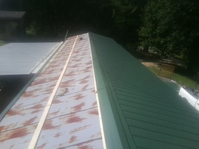 Old rusted panels beside newly installed green metal roofing — Wind Damage Roof Repair by Roofing Brothers in Pine Plains