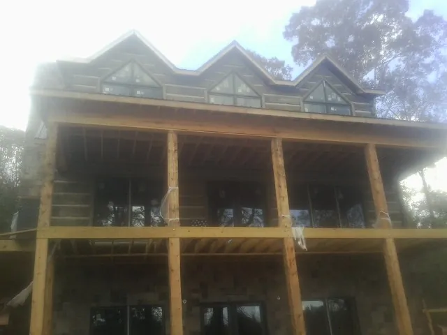 Dormers and porch framing on a large log home under construction — Roof Coating work by our crew in Pine Plains