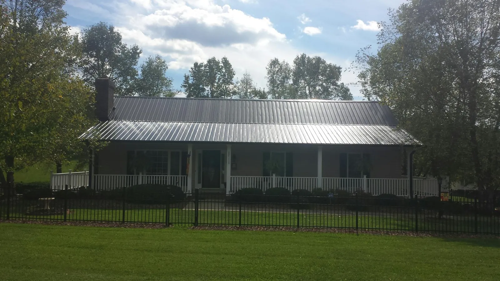 Gray metal roof on a brick ranch with a full width front porch — Gutter Guard Installation work by our crew in Pine Plains