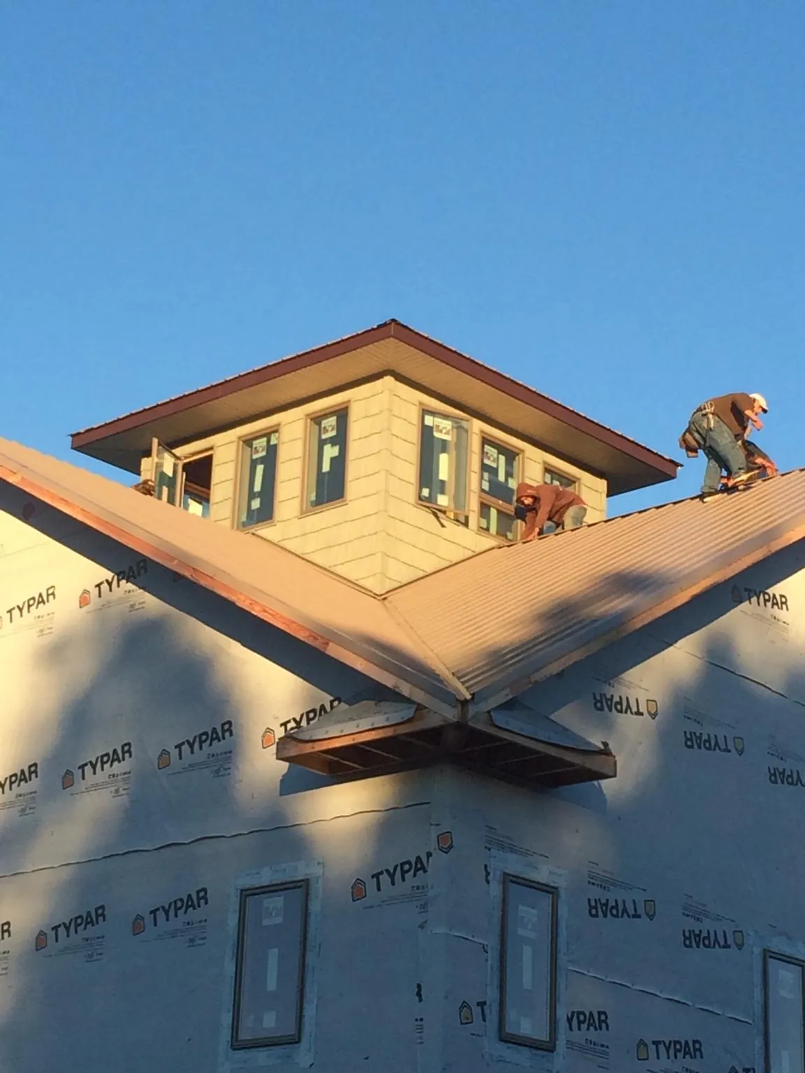 Roofers working around a rooftop cupola on a new metal roof at sunset — Roof Waterproofing in Pine Plains by Roofing Brothers